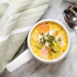 A bowl of Salmon Chowder beside a napkin and spoons.