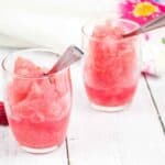 Two glasses of raspberry vodka slush, each topped with fresh raspberries.