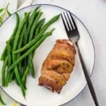 Keto-friendly chicken roll served with fresh green beans on a white plate.