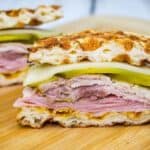 Sliced Keto Cuban Chaffle Sandwich on a wooden board.